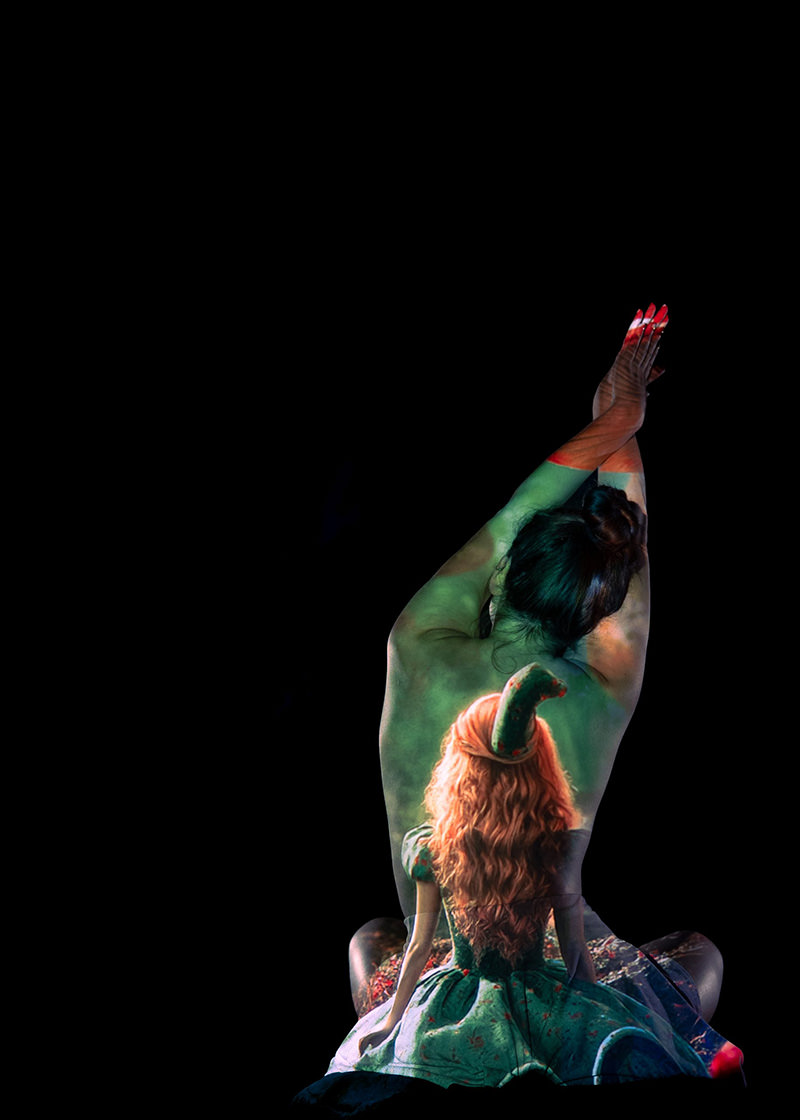 Person with back turned, arms raised, painted with detailed image of a doll in a green dress and hat on their back