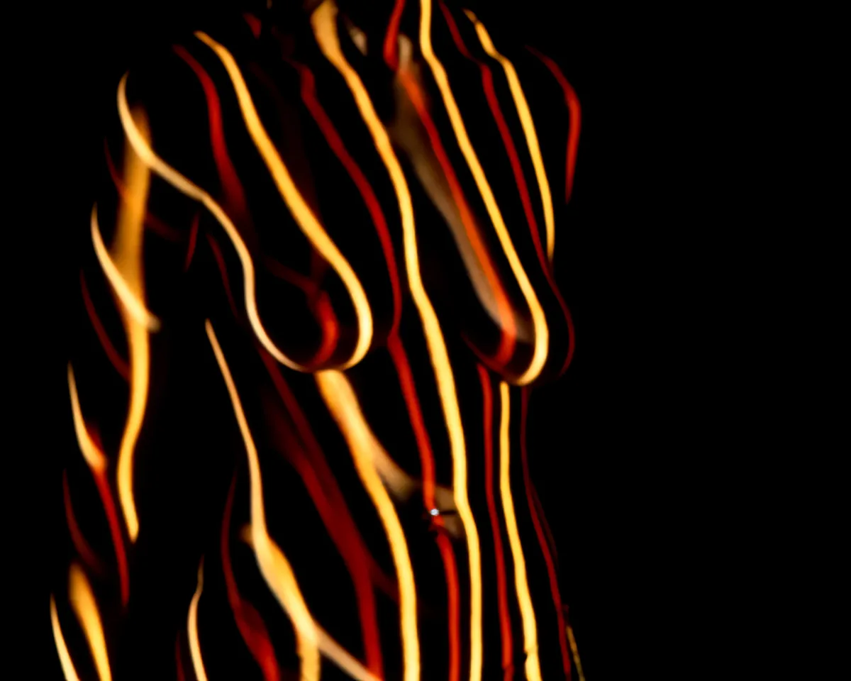 Human torso covered with curved, flowing stripes of yellow and red light against a black background