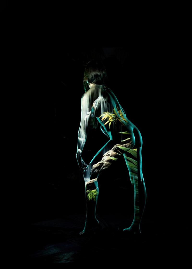 Silhouette of a person bending forward with a detailed projection of a waterfall and green foliage covering their body against a black background