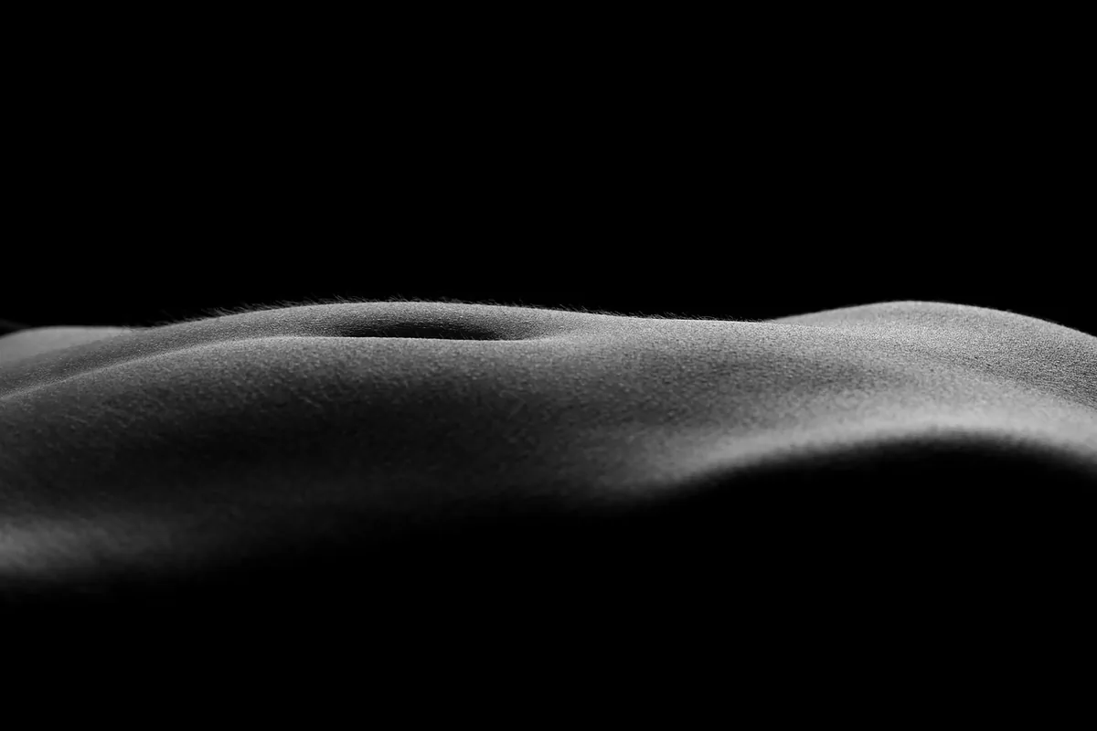 Close-up of a smooth, curved surface highlighted by soft black and white lighting against a dark background
